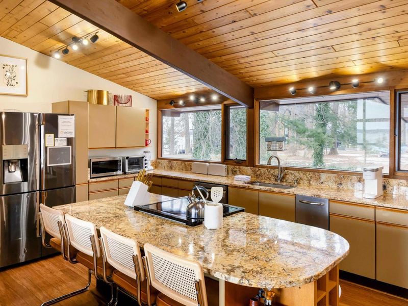 The kitchen offers a spacious, modern design with granite countertops, state-of-the-art appliances, and a large island perfect for meal prep or casual dining, all while enjoying scenic views through expansive windows.