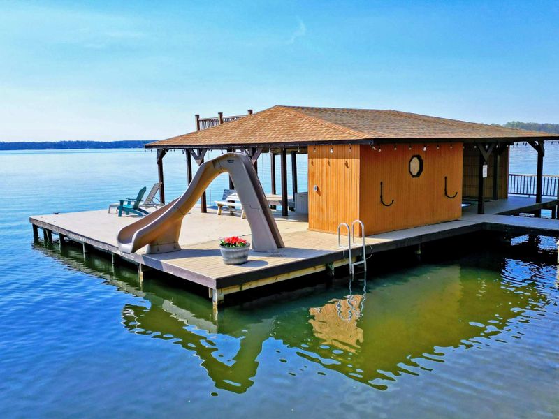 Lakefront boathouse with a water slide, kayak, and easy access to fun activities on the water.