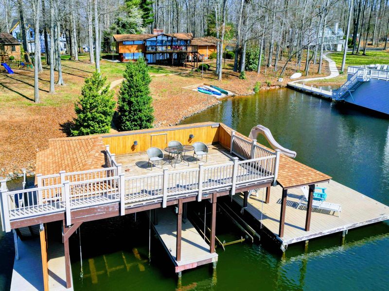 Private waterfront boathouse with an upper-level deck, boat slips, and a spacious sunbathing area overlooking the lake.