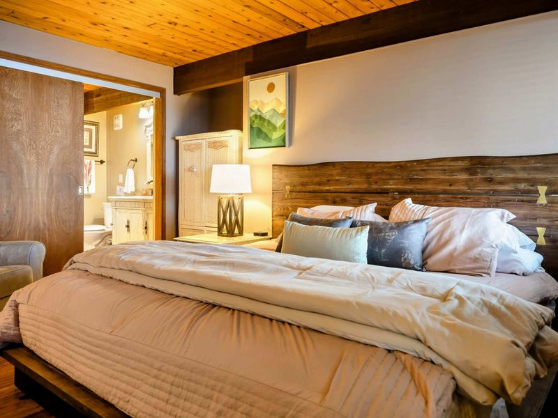 This cozy bedroom features a rustic wooden headboard, inviting bedding, and soft lighting. The ensuite bathroom adds convenience, enhancing the room's relaxing ambiance.