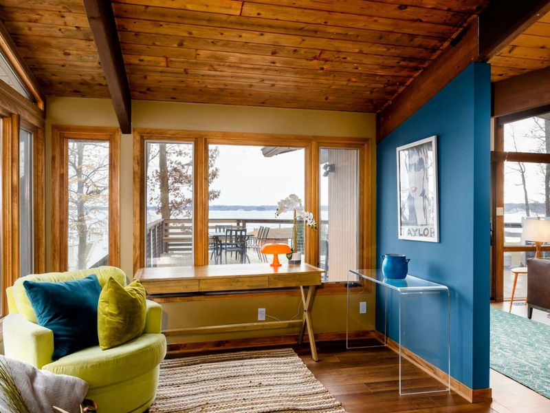 This cozy nook offers a charming spot to unwind with its vibrant lime-green swivel chair and a wooden desk perfectly positioned to enjoy scenic views, making it ideal for reading, relaxing, or a creative workspace.