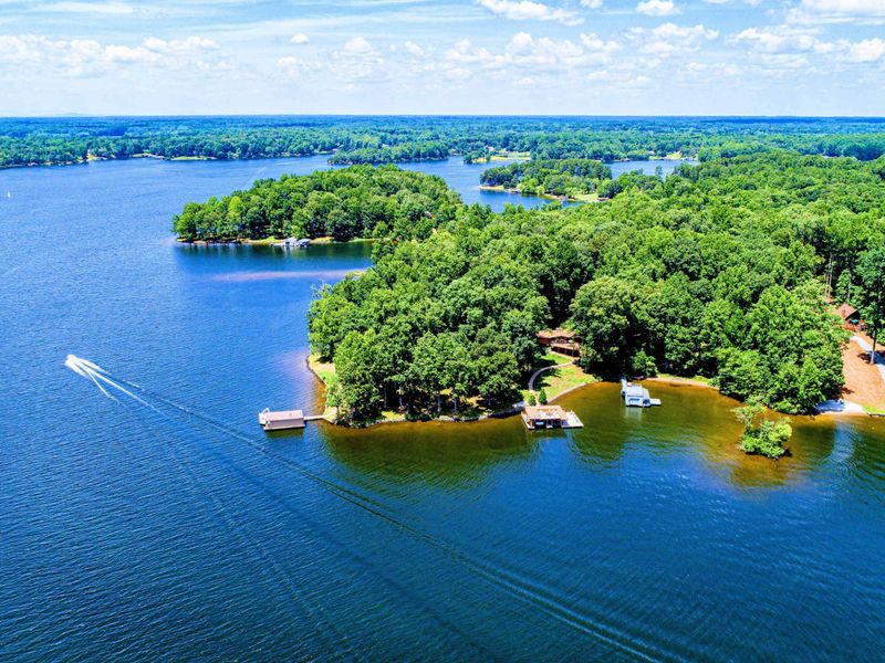 Breathtaking aerial view of a peaceful lakeside retreat surrounded by trees and sparkling blue water.