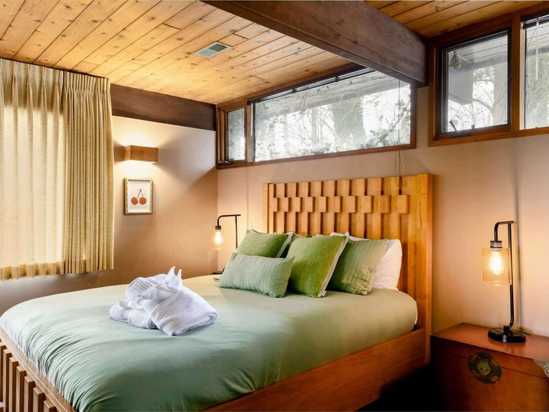 This room features a beautifully crafted wooden bed frame with a unique woven design, complemented by soft lighting and stylish accents for a serene retreat.