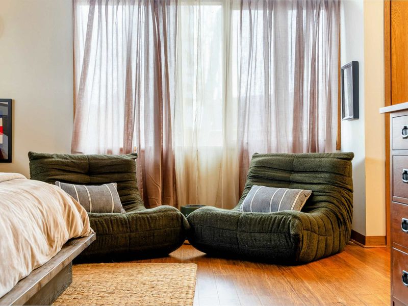 A cozy seating nook in the primary suite features two plush chairs complemented by soft cushions, offering a perfect spot for relaxation near the windows.