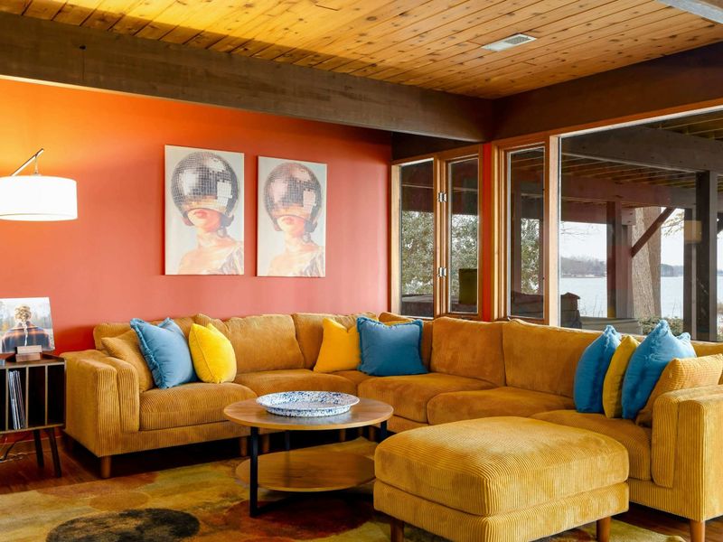 This comfortable seating area features a sectional, modern artwork, and large windows that highlight scenic outdoor views, perfect for relaxing or entertaining.