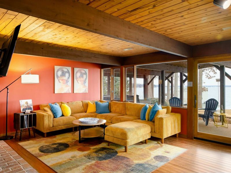 This inviting lounge area offers a spacious sectional, playful artwork, and large windows showcasing stunning outdoor views, creating a cozy and stylish retreat.