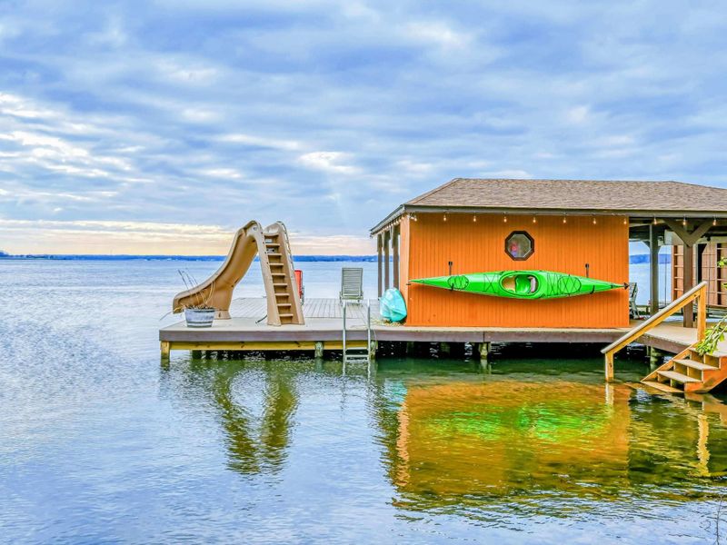 Lakefront boathouse with a water slide, kayak, and easy access to fun activities on the water.