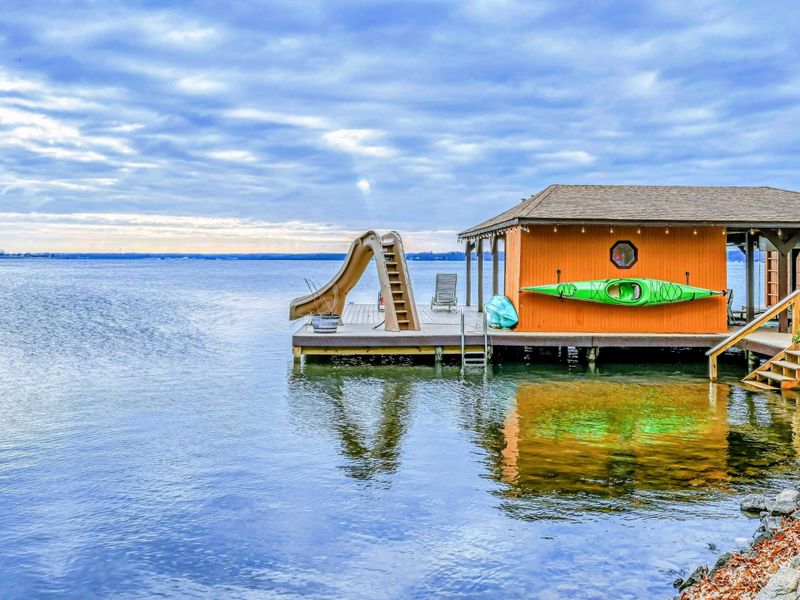 Lakefront boathouse with a water slide, kayak, and easy access to fun activities on the water.