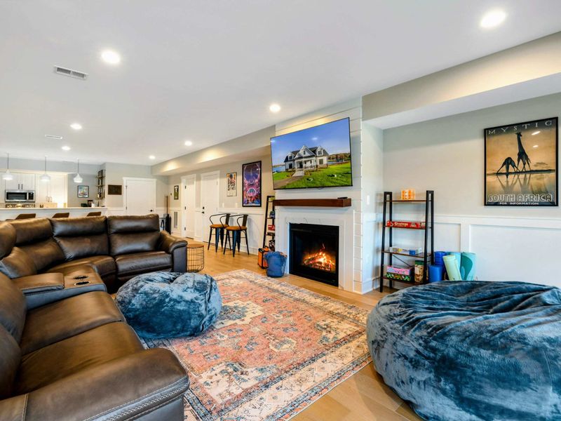 A cozy entertainment area featuring a large leather sectional, plush seating, a stylish rug, and a dining nook, seamlessly connected to a kitchenette and recreation space.