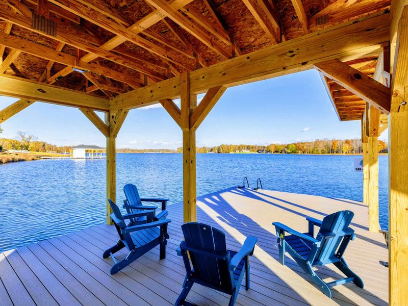 Covered dock with Adirondack chairs overlooking a serene lake, perfect for relaxing and enjoying the view.