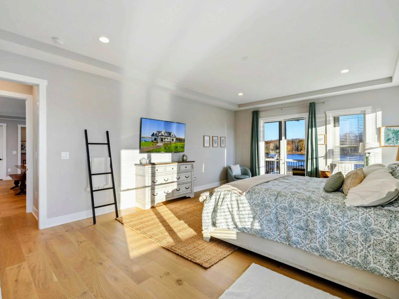 A luxurious and spacious primary bedroom with elegant furnishings, abundant natural light, a private balcony, and an en-suite bathroom.