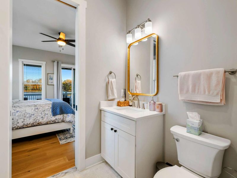 A shared Jack and Jill bathroom featuring a stylish vanity with a gold-framed mirror, soft lighting, and a walk-in shower for added convenience and comfort.