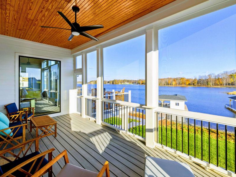 Screened porch with comfortable seating, a ceiling fan, and stunning views of the lake.