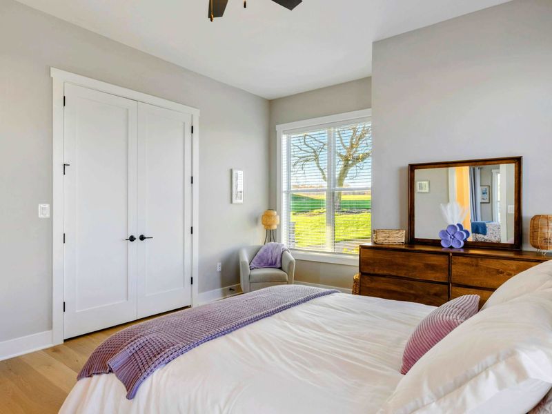 A serene bedroom with natural light, a cozy bed, hardwood floors, and a shared jack and jill bathroom for ultimate comfort.