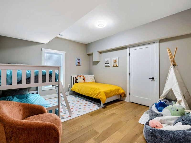 A playful and inviting kids' bedroom with bunk beds, a single bed, a cozy reading nook, and access to a Jack and Jill bathroom for added convenience.