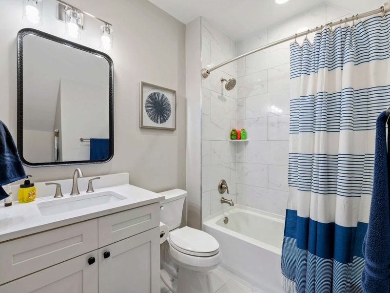 A bright and modern bathroom with a tiled shower and tub, a stylish vanity, and coordinated decor for a clean and inviting feel.