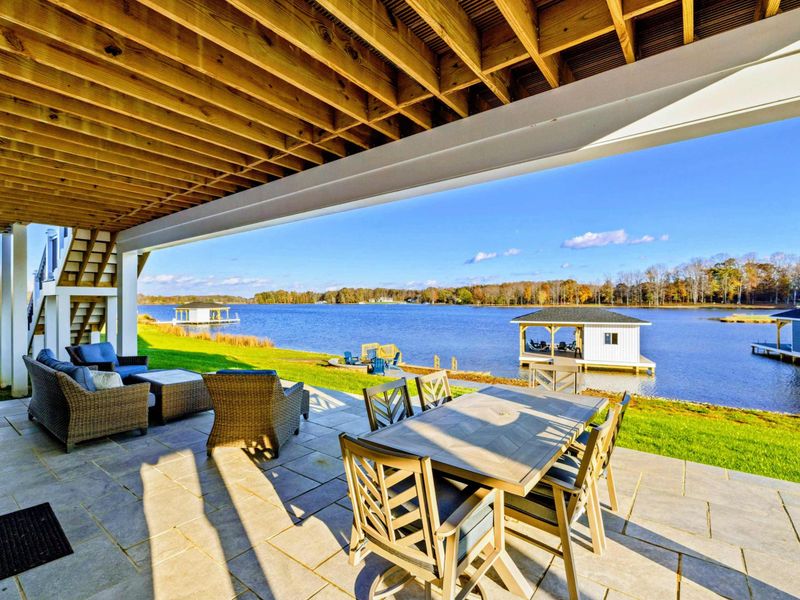 Spacious covered patio with outdoor dining and lounge seating, perfect for enjoying the serene lakeside setting.