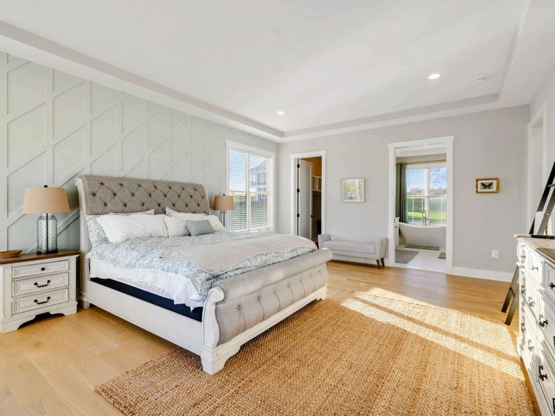 A luxurious and spacious primary bedroom with elegant furnishings, abundant natural light, a private balcony, and an en-suite bathroom.