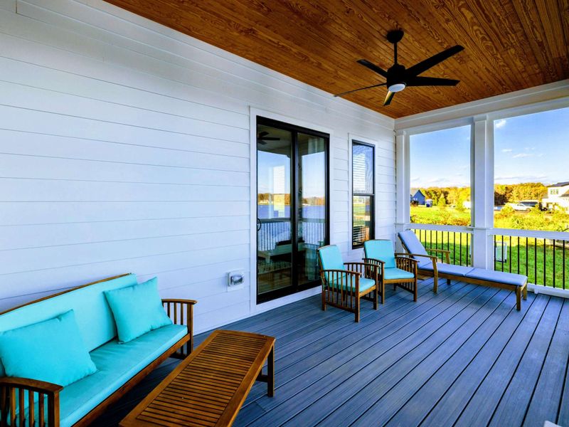 Screened porch with comfortable seating, a ceiling fan, and stunning views of the lake.