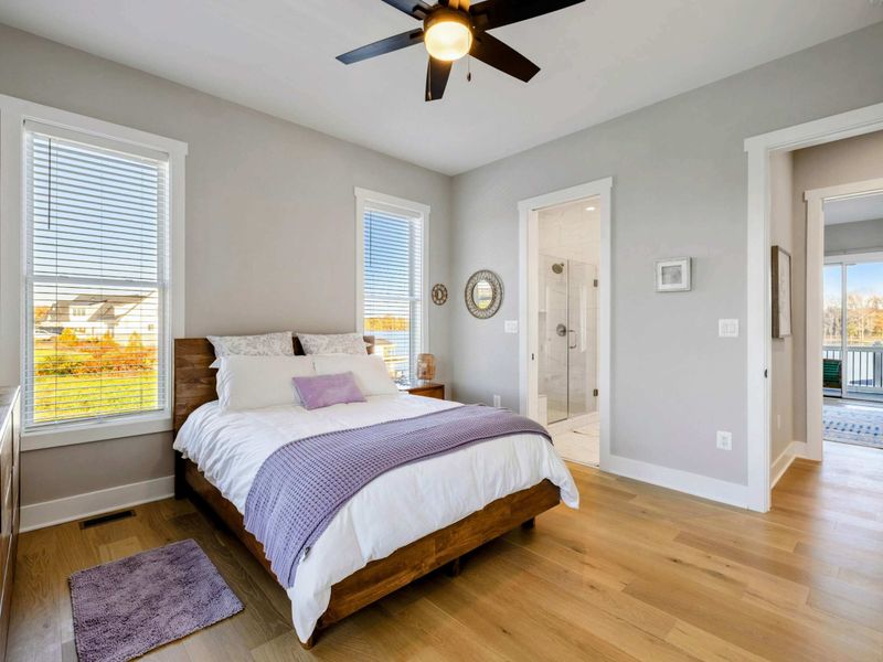 A serene bedroom with natural light, a cozy bed, hardwood floors, and a shared jack and jill bathroom for ultimate comfort.