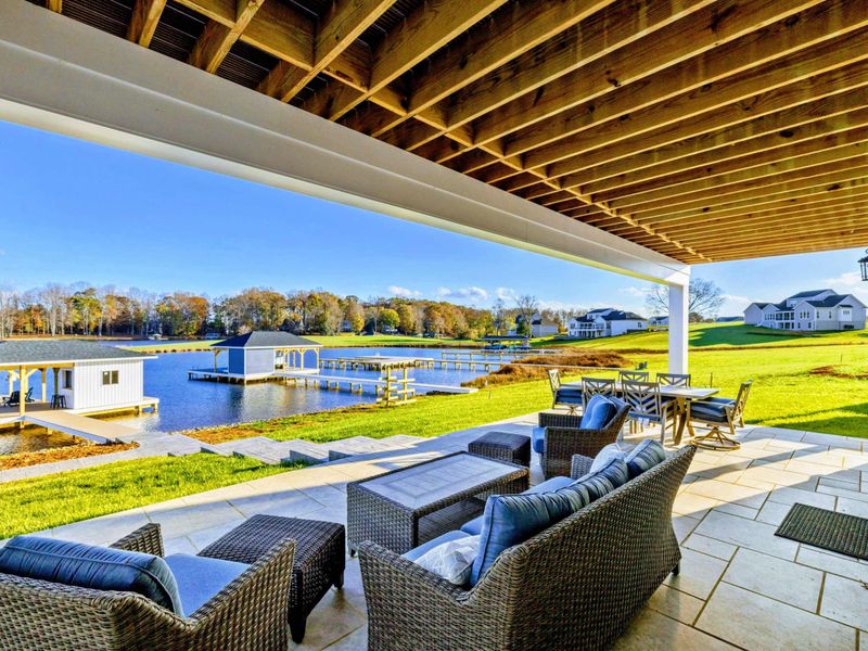 Spacious covered patio with outdoor dining and lounge seating, perfect for enjoying the serene lakeside setting.