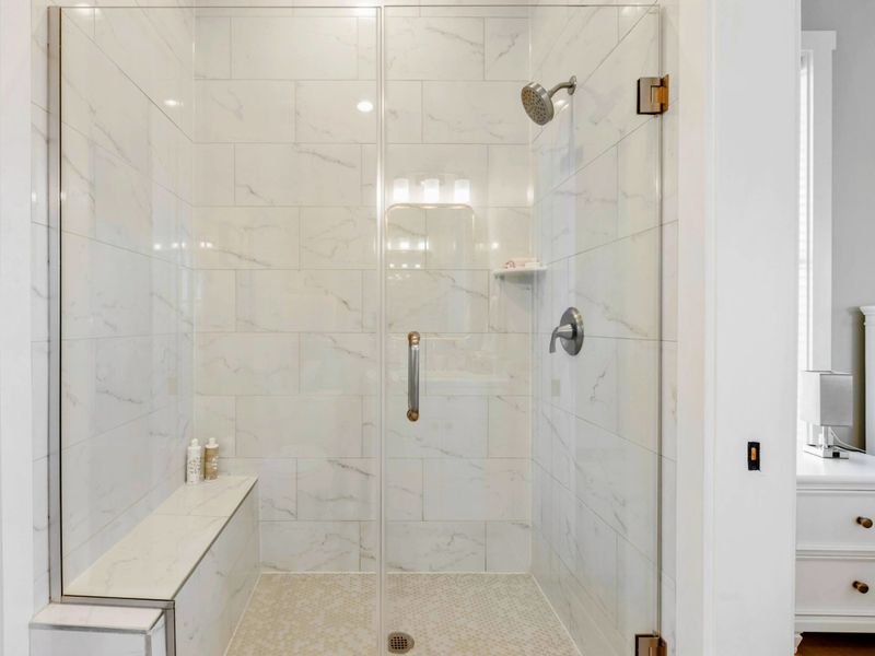 A shared Jack and Jill bathroom featuring a stylish vanity with a gold-framed mirror, soft lighting, and a walk-in shower for added convenience and comfort.