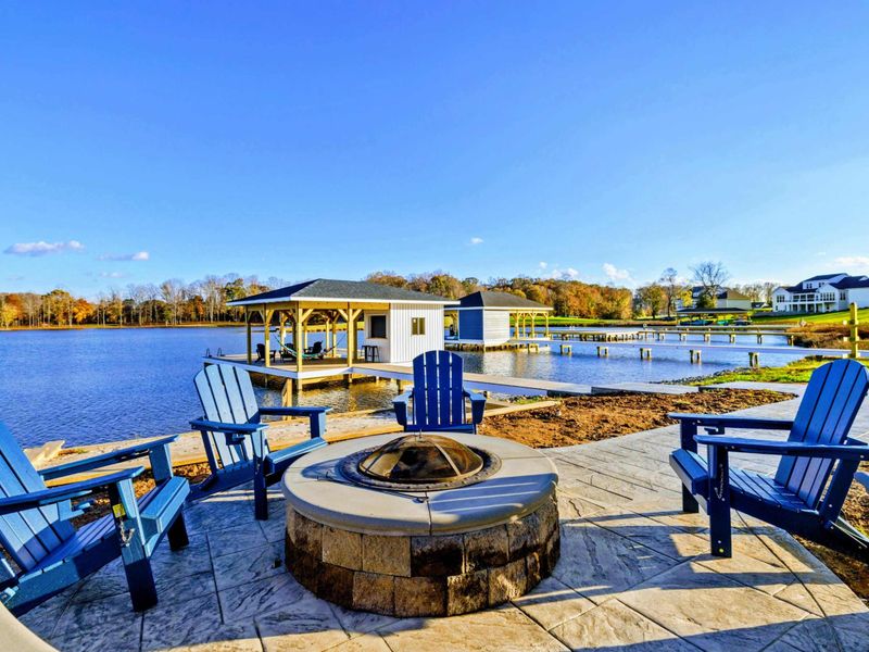 Cozy fire pit seating area overlooking the lake and a dock with a covered boat slip.
