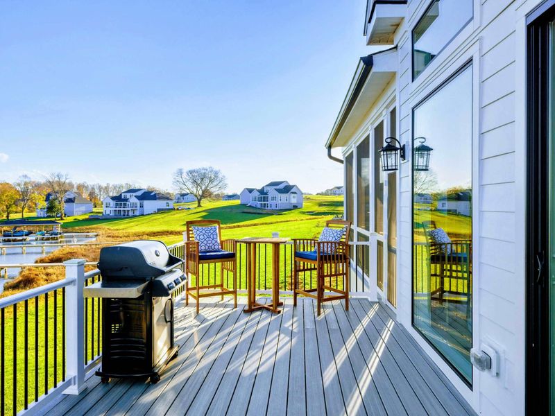 Spacious deck overlooking the lake, featuring rocking chairs and a grill for outdoor relaxation and dining.