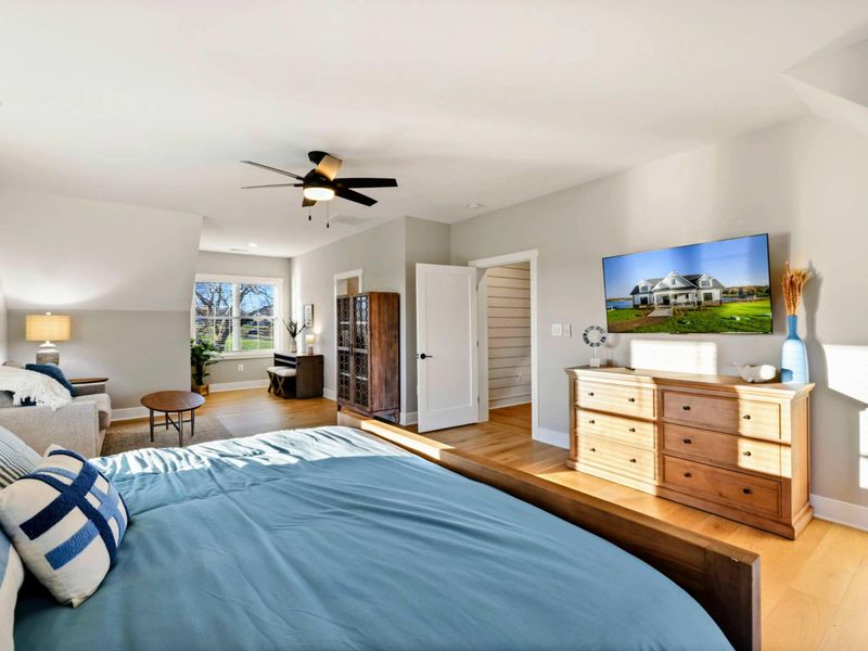 A bright and inviting bedroom with a cozy sitting area, a comfortable bed, a private balcony, and an en-suite bathroom for added convenience.