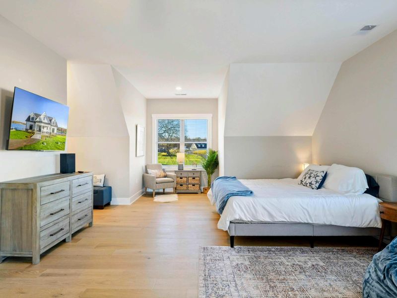 A spacious and bright bedroom with multiple beds, a private balcony, an en-suite bathroom, and a cozy seating area, perfect for accommodating families or groups.