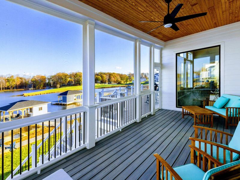 Screened porch with comfortable seating, a ceiling fan, and stunning views of the lake.