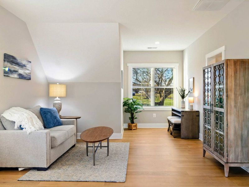 A bright and inviting bedroom with a cozy sitting area, a comfortable bed, a private balcony, and an en-suite bathroom for added convenience.