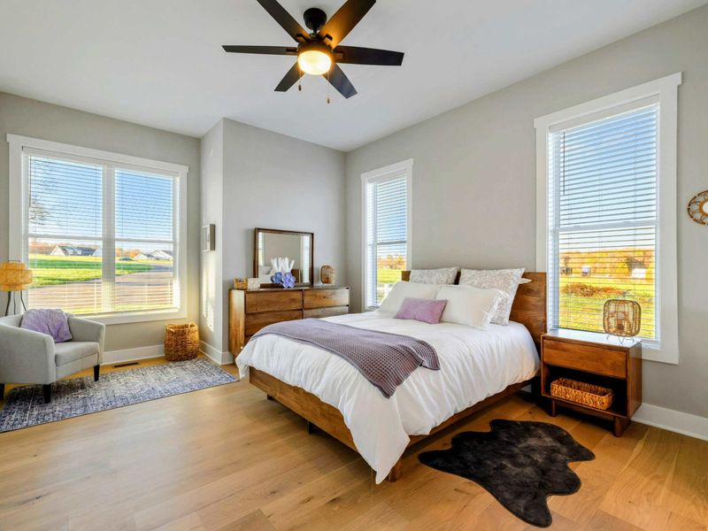 A serene bedroom with natural light, a cozy bed, hardwood floors, and a shared jack and jill bathroom for ultimate comfort.