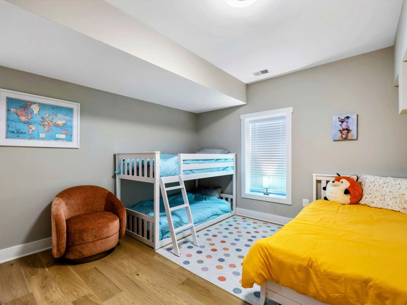 A playful and inviting kids' bedroom with bunk beds, a single bed, a cozy reading nook, and access to a Jack and Jill bathroom for added convenience.