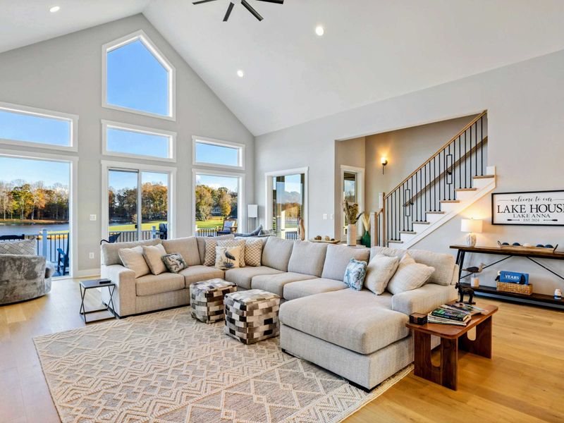 Bright and airy living room with a large sectional sofa, vaulted ceilings, and stunning lake views through expansive windows.