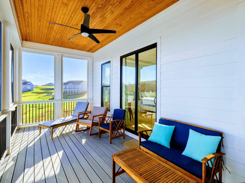 Screened porch with comfortable seating, a ceiling fan, and stunning views of the lake.