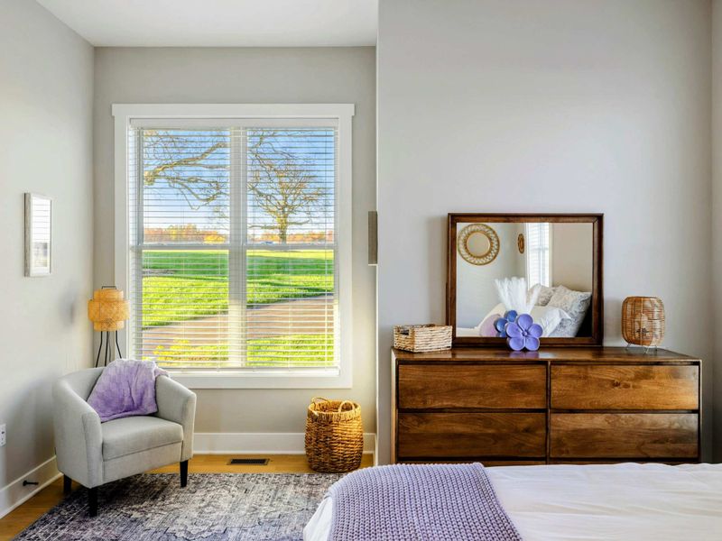 A serene bedroom with natural light, a cozy bed, hardwood floors, and a shared jack and jill bathroom for ultimate comfort.
