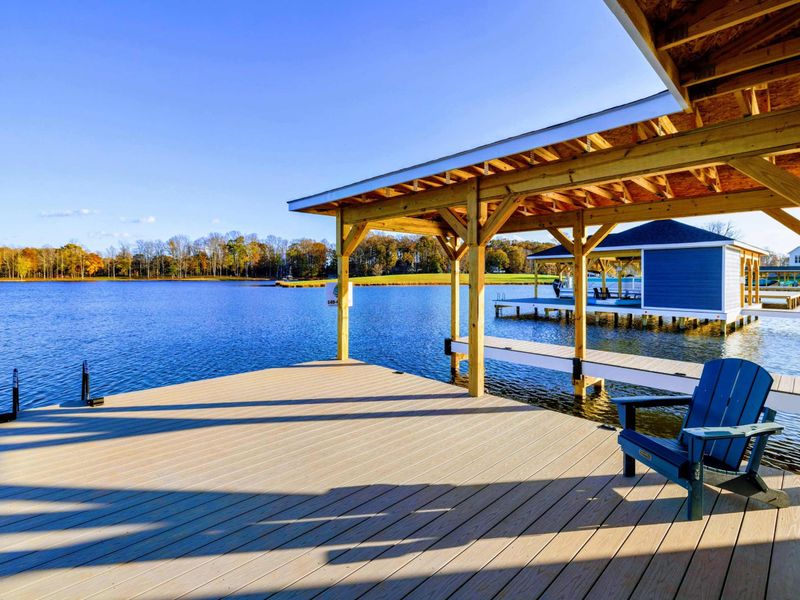 Covered dock with Adirondack chairs overlooking a serene lake, perfect for relaxing and enjoying the view.