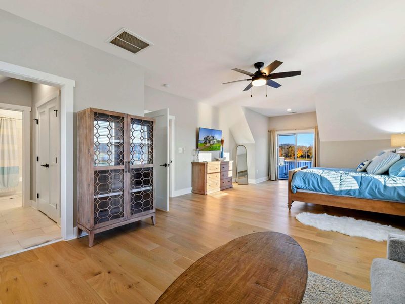 A bright and inviting bedroom with a cozy sitting area, a comfortable bed, a private balcony, and an en-suite bathroom for added convenience.
