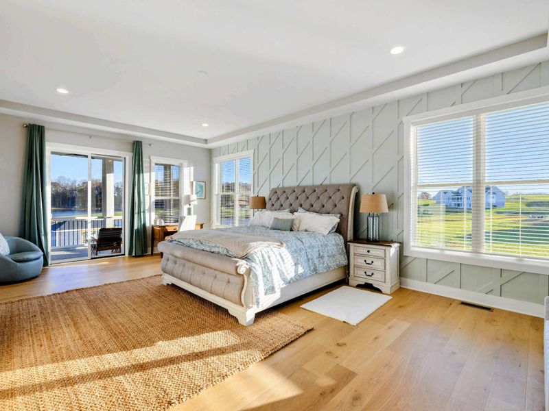 A luxurious and spacious primary bedroom with elegant furnishings, abundant natural light, a private balcony, and an en-suite bathroom.