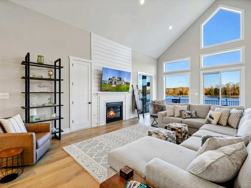 Bright and airy living room with a large sectional sofa, vaulted ceilings, and stunning lake views through expansive windows.