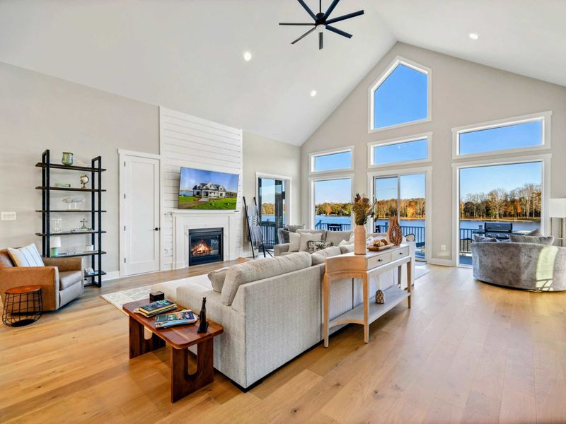 Bright and airy living room with a large sectional sofa, vaulted ceilings, and stunning lake views through expansive windows.