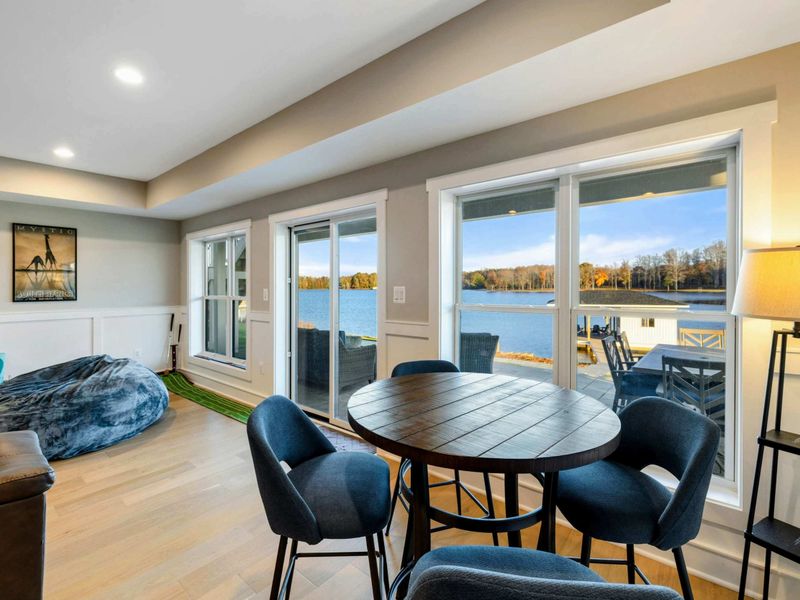 A cozy entertainment area featuring a large leather sectional, plush seating, a stylish rug, and a dining nook, seamlessly connected to a kitchenette and recreation space.