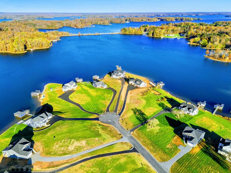 Aerial view of a tranquil lakeside community featuring spacious homes, green lawns, and private docks with stunning water views.