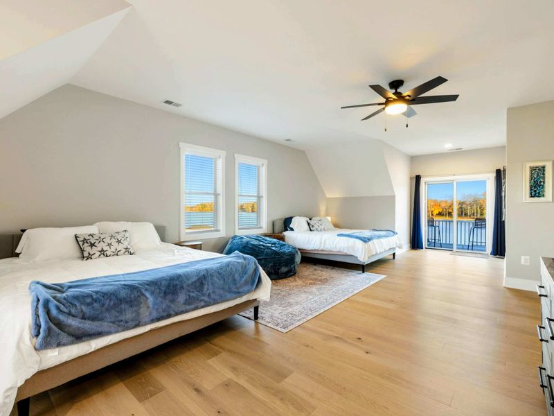 A spacious and bright bedroom with multiple beds, a private balcony, an en-suite bathroom, and a cozy seating area, perfect for accommodating families or groups.