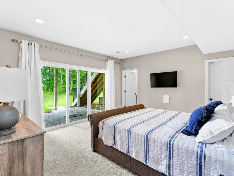 A comfortable bedroom featuring a king bed, stylish decor, sliding glass doors leading to a private patio with outdoor views, and an ensuite bathroom for added convenience.