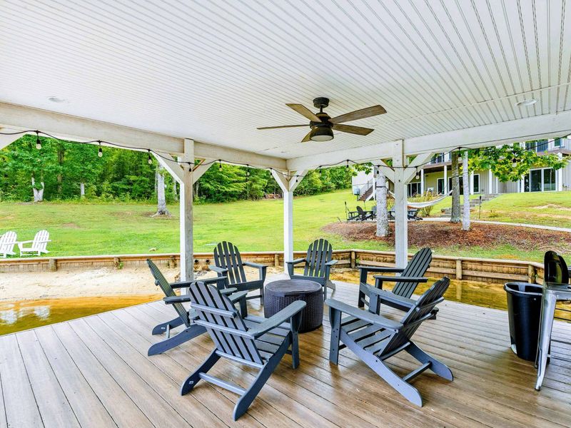 A picturesque waterfront dock featuring covered seating, lounge chairs, and easy access to the sandy beach and spacious backyard.