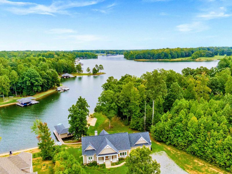 A picturesque lakeside property featuring a spacious home, private dock, sandy shoreline, and lush greenery for a tranquil retreat.