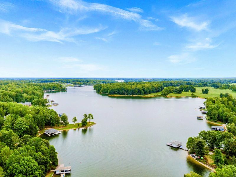 A breathtaking aerial view of Lake Anna showcasing its serene blue waters, lush green shoreline, and a vibrant, colorful sunset.