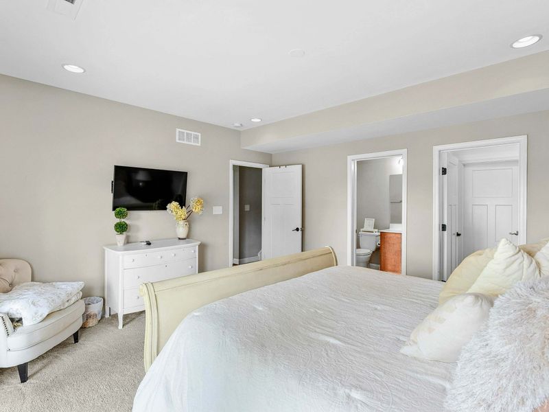 A tranquil bedroom with a king bed, cozy decor, sliding glass doors opening to a patio with lush outdoor views, and an ensuite bathroom for added convenience.